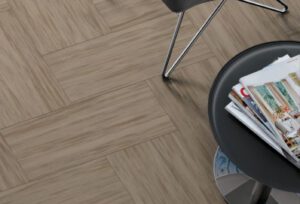 Overhead view of caramel colored VCT 12x24 inch tile in herringbone pattern. End table partially shown.
