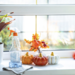Autumn inspired counter top with a cleaning spray bottle, and ceramic mini 4 orange and white pumpkins and a fall plant